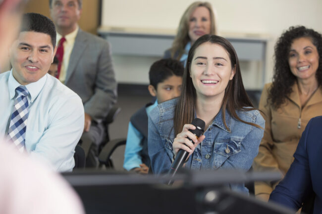 Young woman asks question during town hall meeting