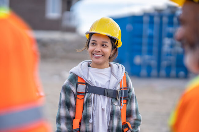 Female construction worker standing among her coworkers.