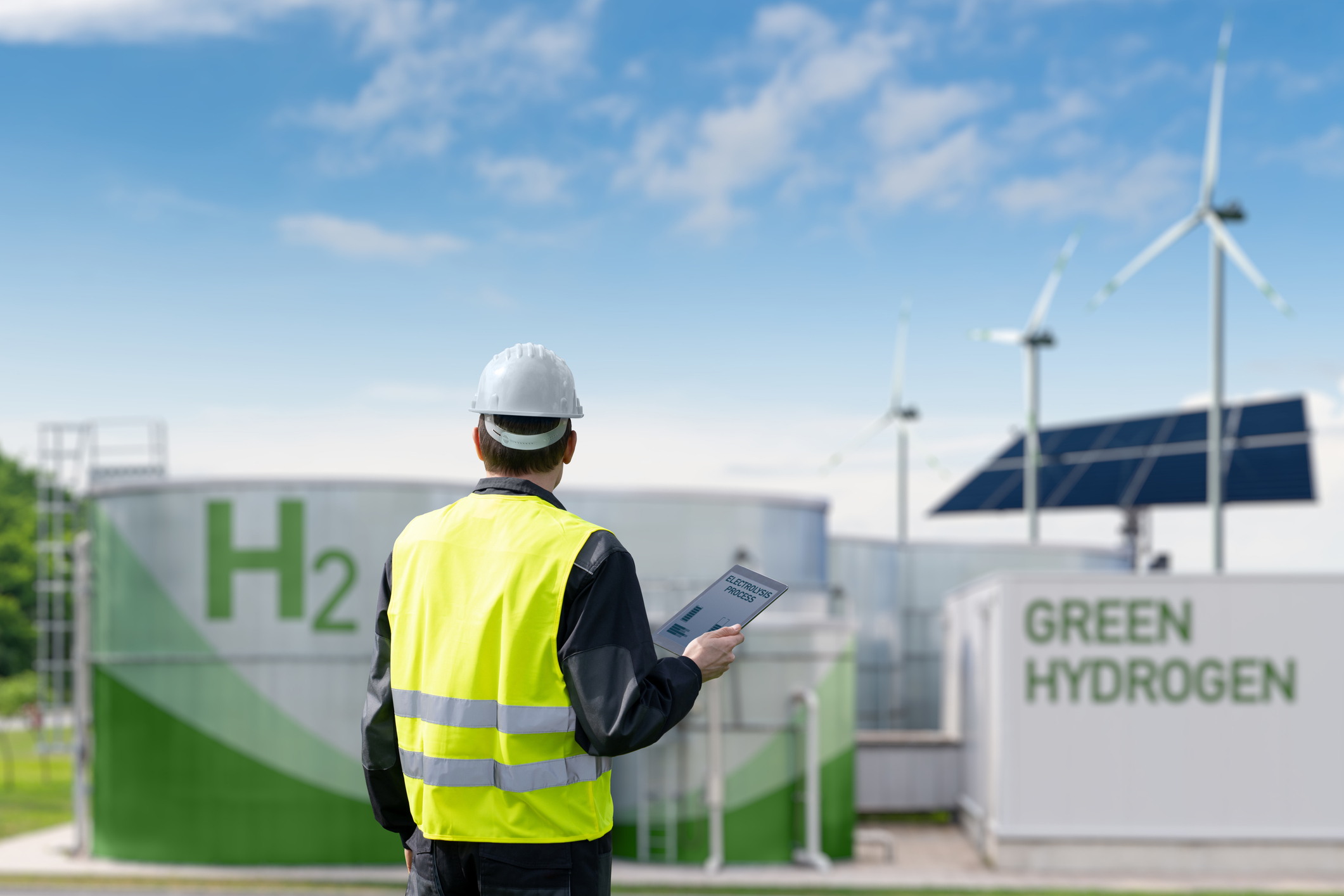 Photo illustration. Engineer with tablet computer on a background of Green Hydrogen factory